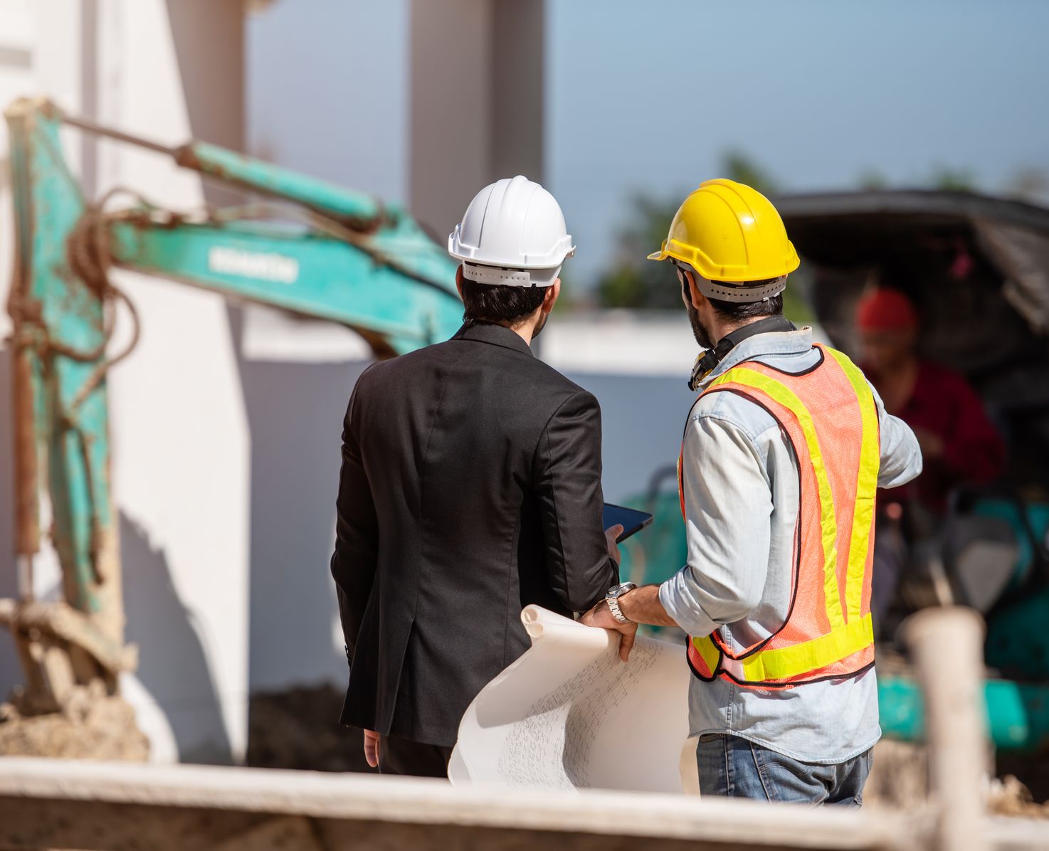 Two men in construction uniforms overseeing a construction site